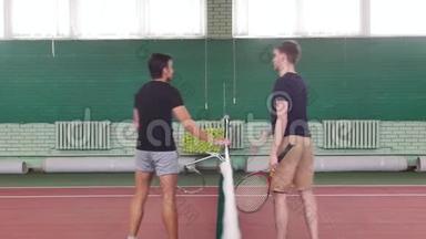 网球场上的两个年轻的健康男子走近网球场，握手